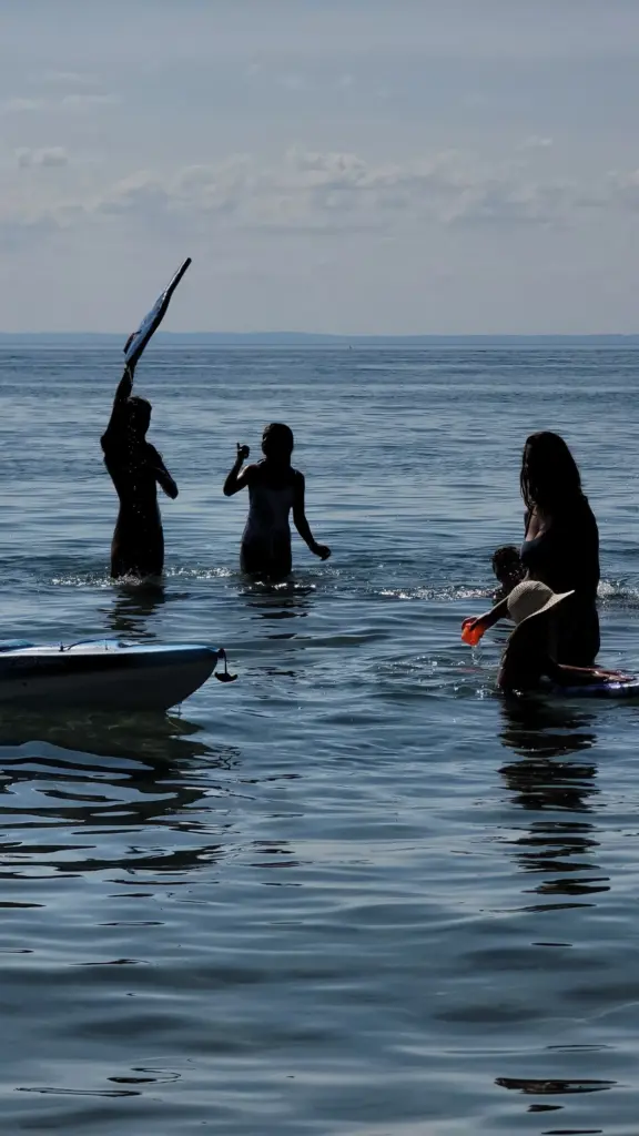 Playful moment in the water: Silhouettes of two people swimming or doing a handstand on the beach.
