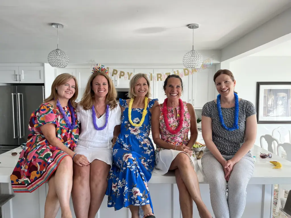 Group of happy women wearing floral leis at a CARI bachelorette party or retreat celebration.