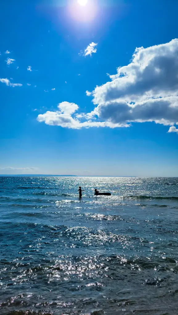 Water sports activities at CARI: Windsurfing or sailing silhouette under a bright blue sky.